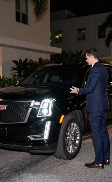A sleek black luxury car parked beside a modern Miami waterfront residence at sunset.