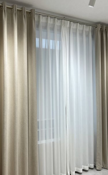 Sunlight filtering through soft, flowing cream curtains in a cozy living room.