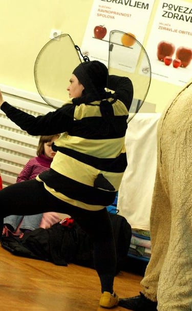 Actors in bee and bear costumes performing a children's play for an attentive audience.