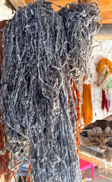 Fardos de hilo de lana cruda de color gris y naranja colgados en un taller de tejido textil tradicio