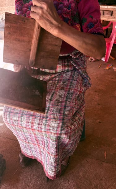 Una tejedora guatemalteca que utiliza herramientas tradicionales de cardado de lana de madera 