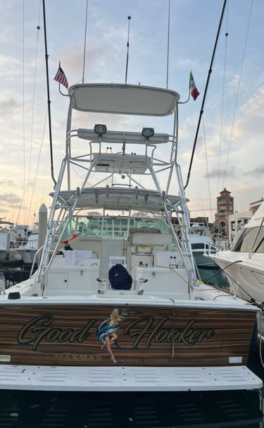 A luxury sport fishing boat docked in a marina featuring a wooden transom with custom typography.