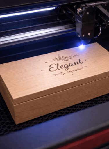 A precision laser engraving machine etching a custom design onto a wooden gift box.