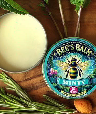 Tin of Bee's Balm Minty Fragrance Surrounded by Peppermint, almonds, Rosemary Sprigs & essential oil