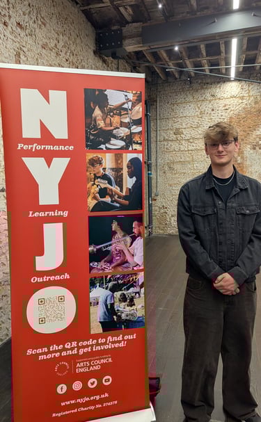 An image of Jamie Walker standing next to a NYJO sign