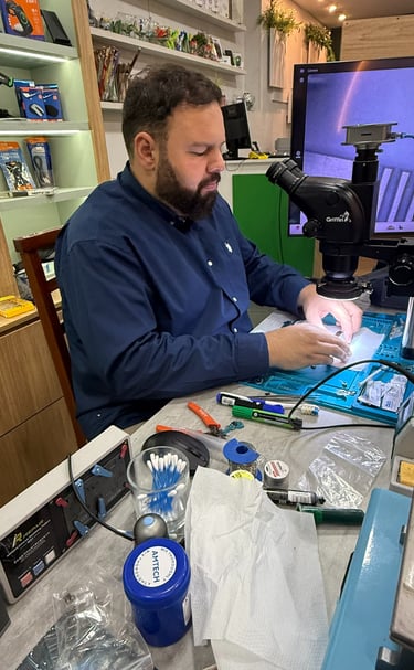 Professional technician performing micro-soldering on a circuit board using a digital microscope.