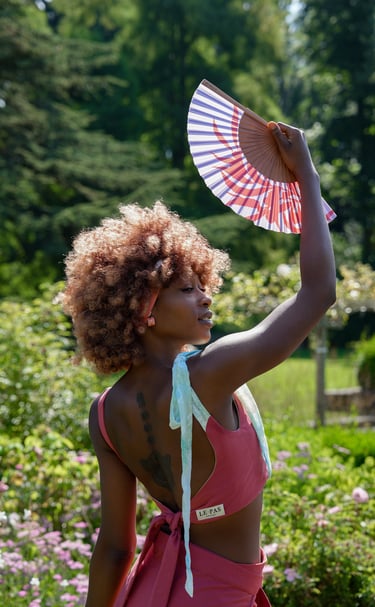 a woman model in a pink bikini suit holding a fan