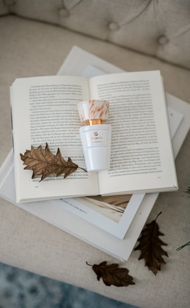 Un elegante flacone di profumo Olfazeta della linea Chogan poggia delicatamente su un libro aperto,
