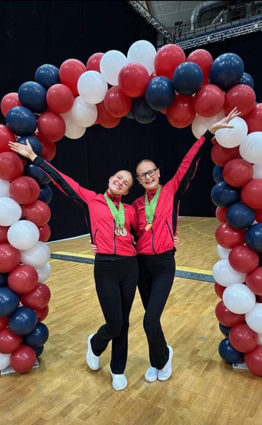 two women standing in front of a large arch shaped balloon