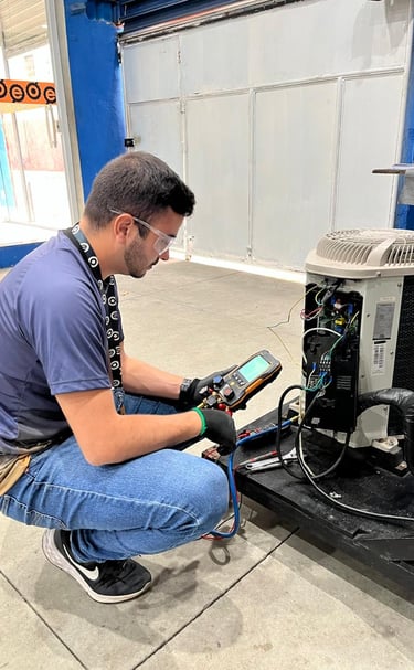 An HVAC technician uses a digital manifold gauge to perform AC repair on an outdoor condenser unit.