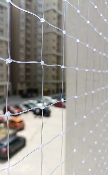 Technician carefully fixing a pigeon net on a balcony railing
