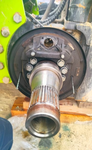 Close-up of a heavy machinery axle shaft and brake assembly undergoing mechanical repair.