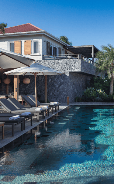 a pool with lounge chairs and umbrellas at villa noah st barth