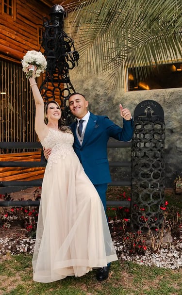 Recién casados celebrando sonriendo a cámara. La novia levanta el ramo y disfrutan de su momento juntos en Quito, Ecuador