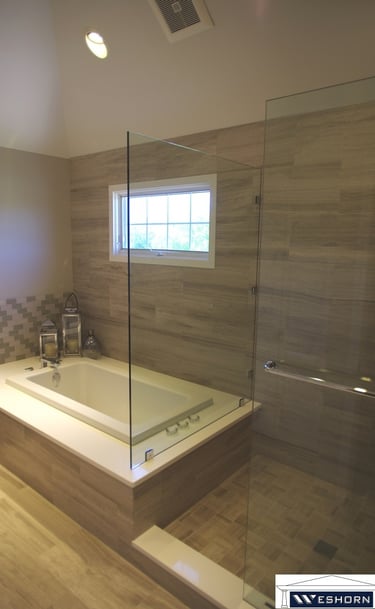 Modern master bathroom featuring a soaking tub next to a glass walk-in shower with neutral stone tile.