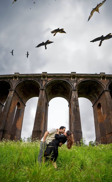 Couple kissing beneath a historic railway viaduct in Kent countryside, captured by Fred Art Studio.