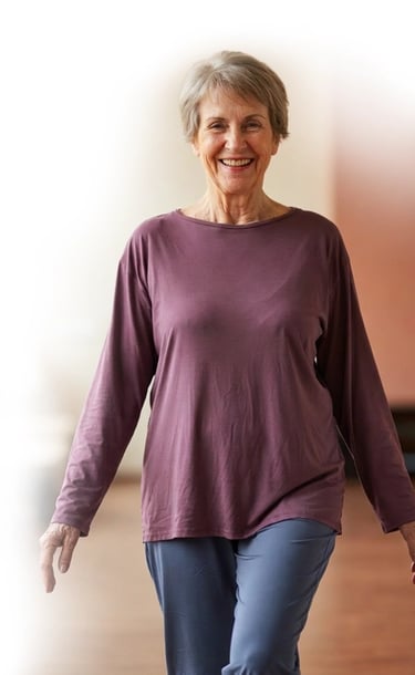A smiling senior woman walking in a bright studio wearing comfortable activewear stem cell patient.