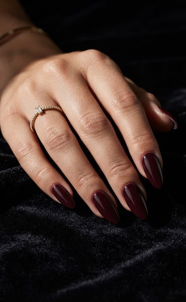 Macro editorial close-up of a hand with long, sculpted luxury nails resting on a dark velvet surface, dramatic side lighting highlighting the glossy gel texture, high-contrast shadows.