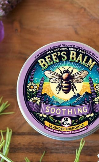 Tin of Soothing Bee's Balm surrounded by Lavender Sprays and buds & Chamomile flowers and 