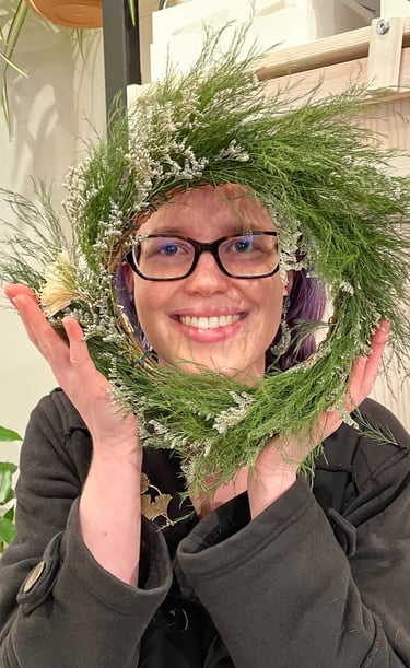 a woman holding a wreath of pine needles