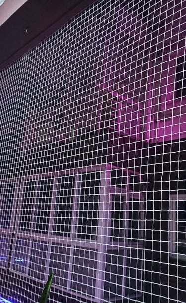 Wide shot showing a vibrant family relaxing safely behind a newly installed balcony net.
