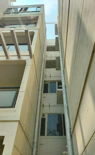 Wide shot of a multi-story building in Whitefield with freshly installed safety nets on all windows.