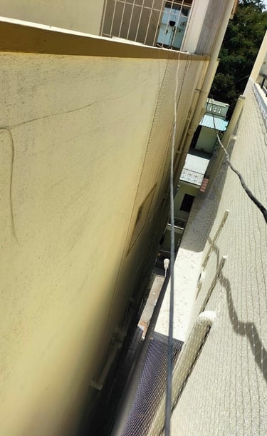 Wide view of a residential building with multiple pigeon nets installed by Arjilli Enterprises.