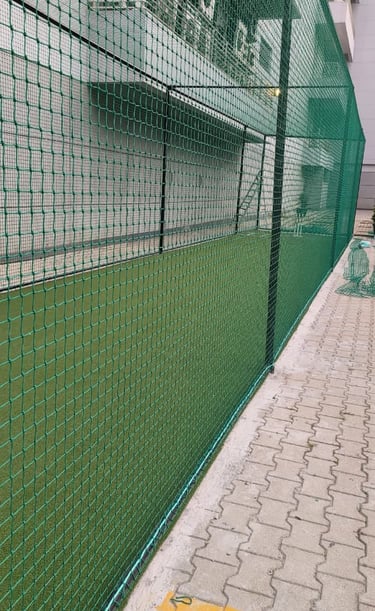 Wide shot showing a football field surrounded by sturdy protective nets installed by Arjilli Enterpr