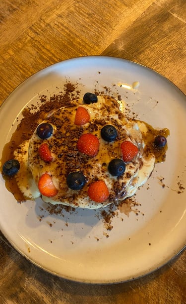 a plate of pancakes with berries on a table