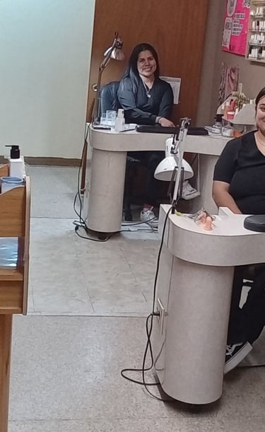 Student nail technicians sitting at individual manicure stations in a college beauty salon.