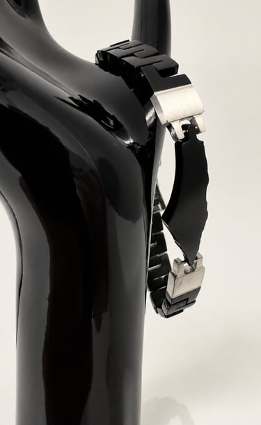 Sleek black stainless steel link bracelet displayed on a glossy black mannequin hand.