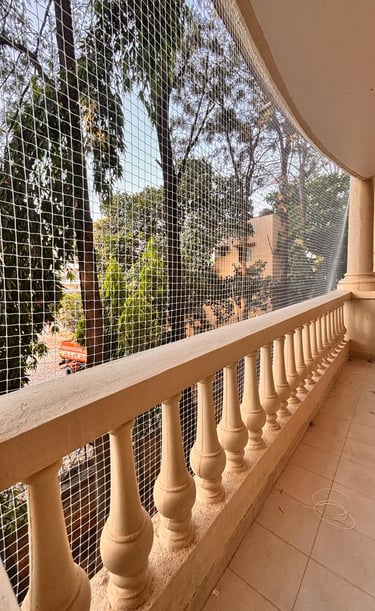 Wide-angle shot capturing a rooftop fully covered with arjilli safety pigeon nets against a bustling