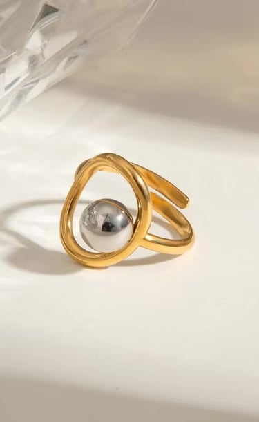 Anillo dorado minimalista con diseño escultórico y esfera central, joyería elegante de Moreina Joyería.