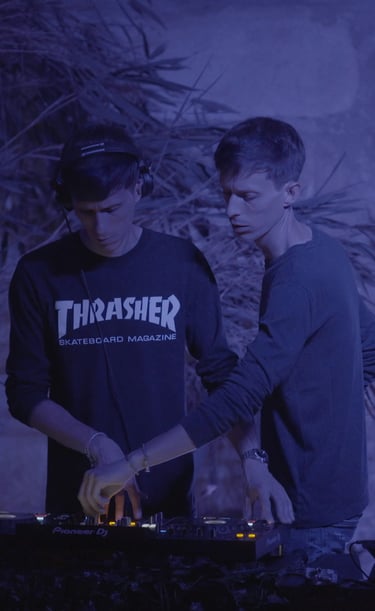 two men standing in front of a wall with a dj booth