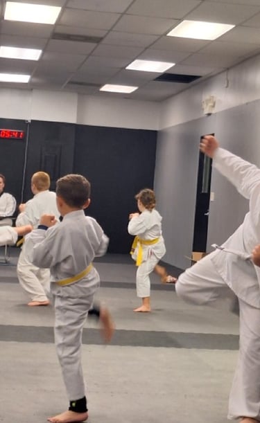 Young students practicing karate kicks during a martial arts class in a studio.