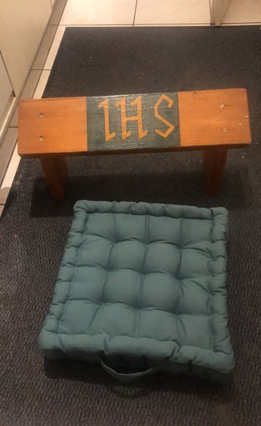 Sitting on a prayer stool while kneeling on the cushion, praying through rosary as long as it takes.