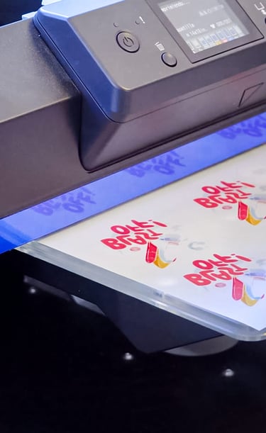 An Epson industrial inkjet printer creating custom colorful logo transfers on a clear film sheet.