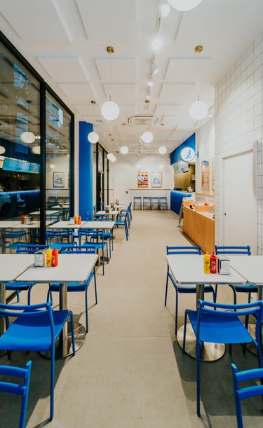 Interior de Flipa desde la entrada, con sillas azules, azulejos blancos y ambiente moderno
