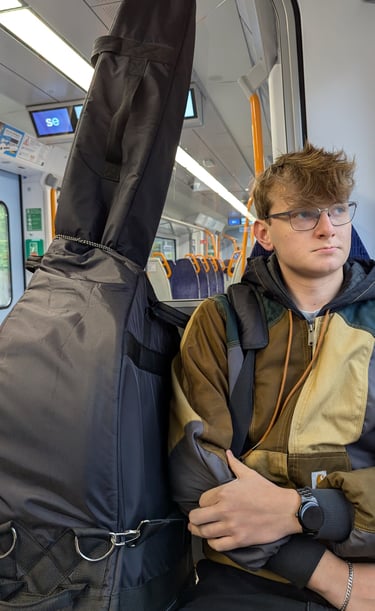 An image of Jamie Walker travelling on a train with his Double Bass