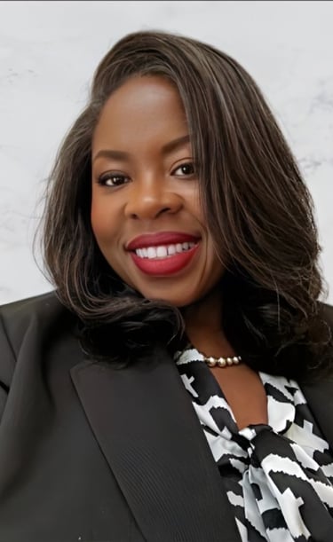 Professional headshot of a smiling woman in a black blazer and patterned blouse.