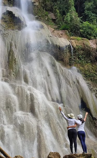 two people standing in front of a waterfall