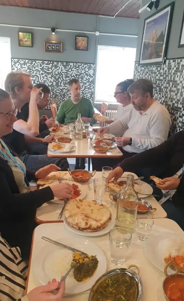 A group of friends sharing authentic Indian cuisine including curry and naan bread at a restaurant.