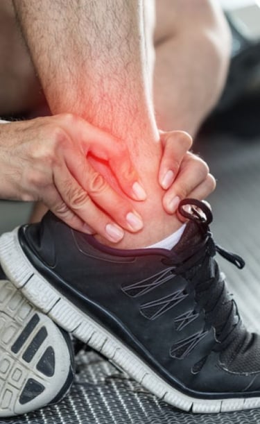 Homem vestindo tênis de corrida com a mão na região do tornozelo