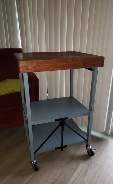 Industrial rolling kitchen cart with a thick wood butcher block top and gray metal storage shelves.