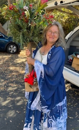 smiling lady in blue and white holding a holiday tree decoration