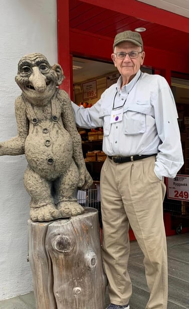 a man stands next to a sculpture of a troll