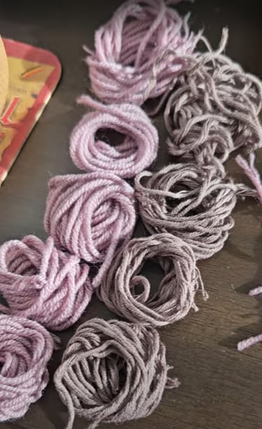 Small bundles of pink and brown wool yarn coiled on a dark wooden surface for knitting crafts.