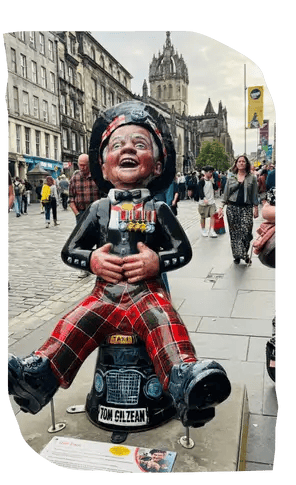 Oor Wullie statue wearing tartan trousers, holding his belly and laughing