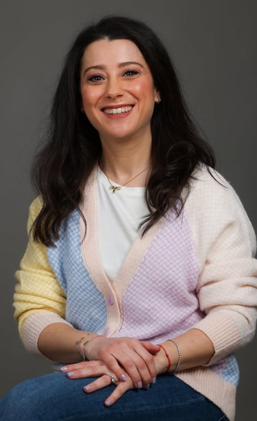 a woman in a colorful sweater and jeans sitting on a chair