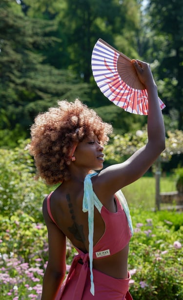 a woman model in a pink bikini suit holding a fan